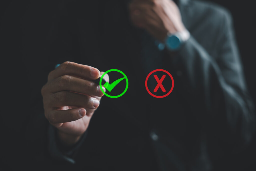 Close-up of businessman hand, in a suit, touching a green checkmark on a virtual screen. Consideration of yes or no choices. True and false symbols evaluated. Think With Yes Or No Choice.
